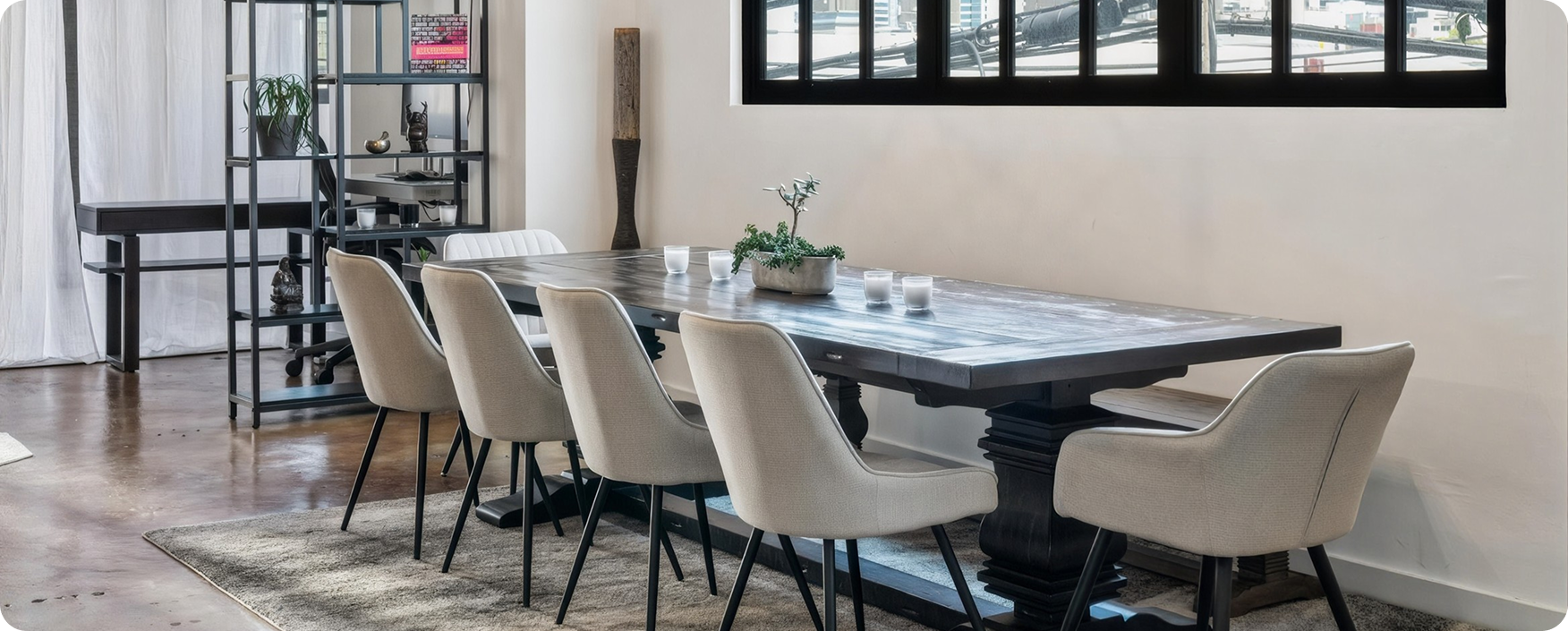 Dining room with a large table and chairs, a flower vase, glasses, and other objects on the table