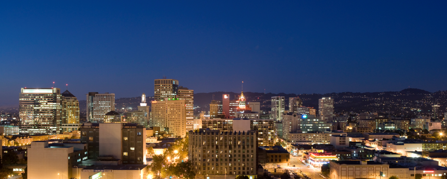 City skyline at night from the top of a hill, with skyscrapers, towers