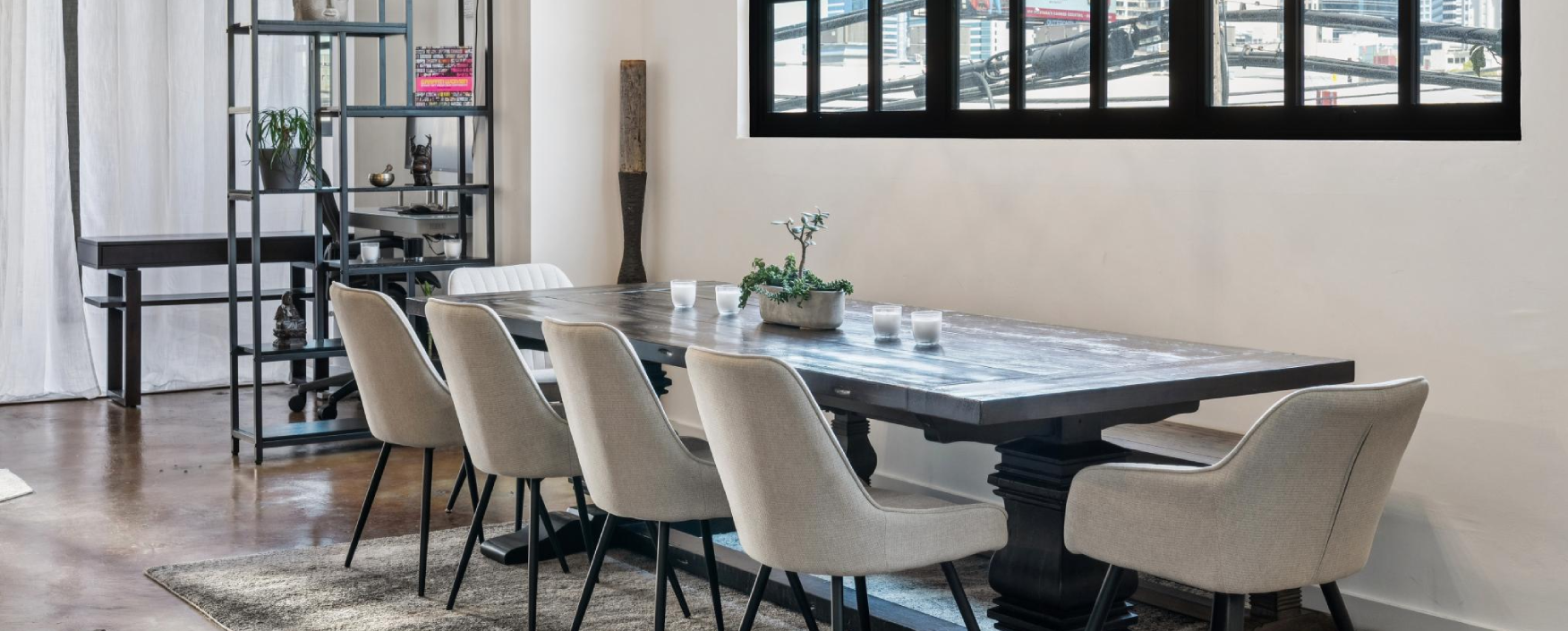 Dining room with a large table and chairs, a houseplant, glasses, and other objects on the table