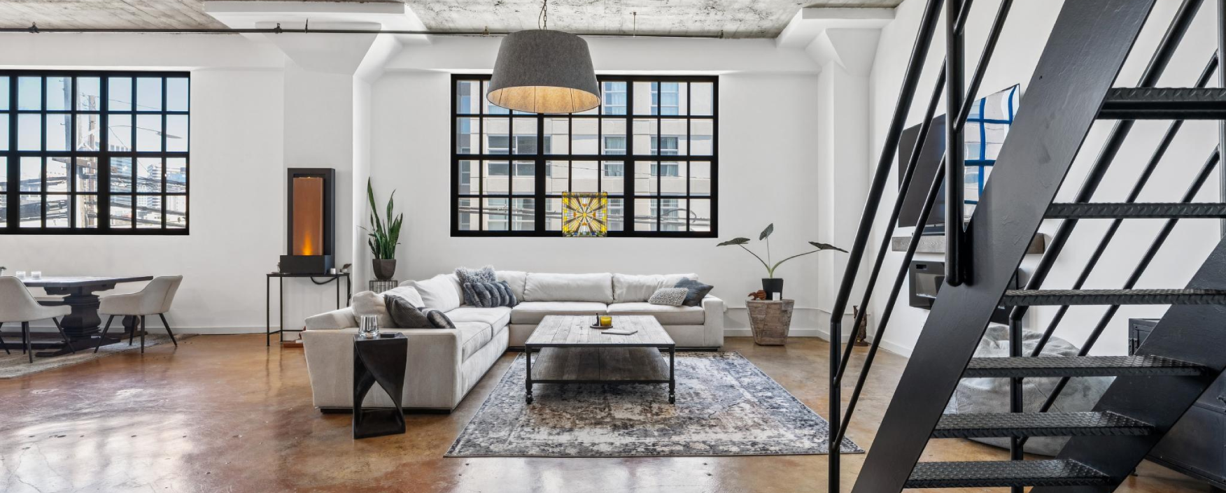 Living room filled with furniture such as a sofa set with cushions, side tables with decors, houseplants, a dining table